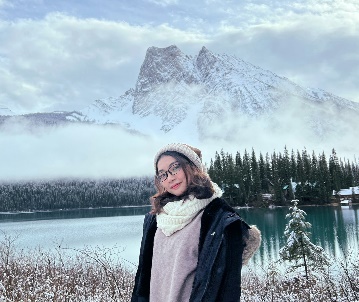 A person standing in front of a lake with a mountain in the background

Description automatically generated with medium confidence