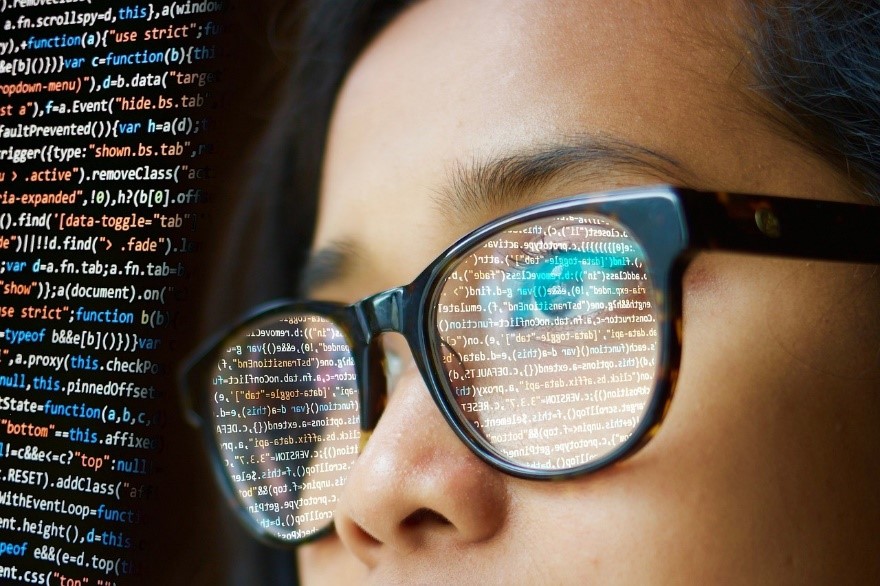 Photograph of woman in glasses reading code