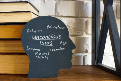 Black Silhouette of a person's head with these words written on it: Unconscious bias, religion, education, age, gender, income, mental ability
