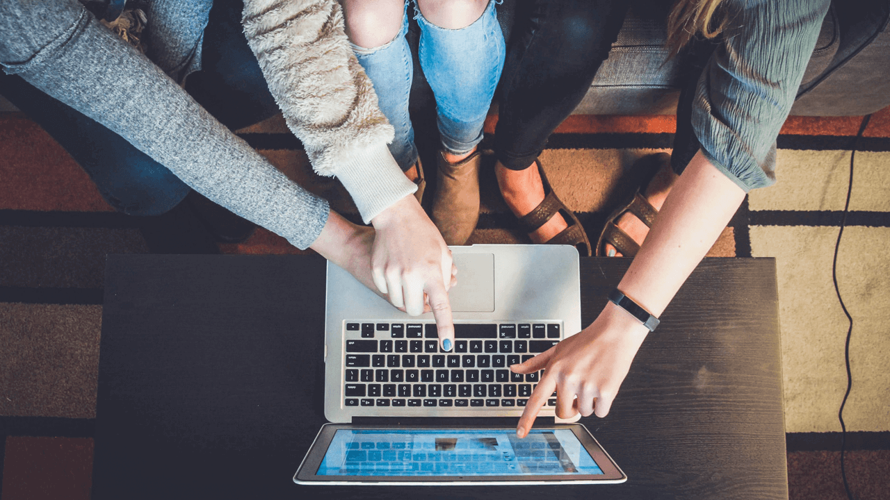 three people, each pointing at a laptop screen