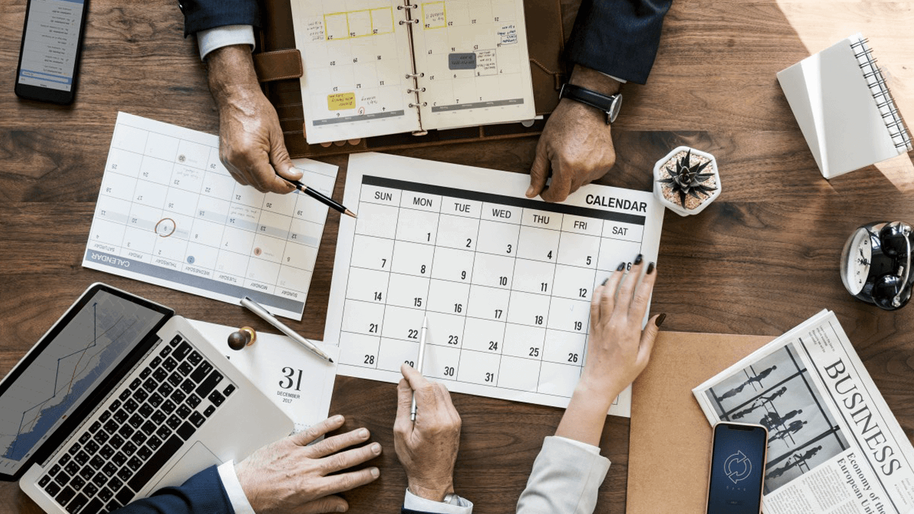 people pointing at a calendar on the table between them