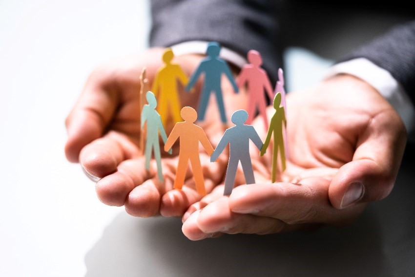 Image of hand holding a paper cutting in a shape that people holding hands in circles